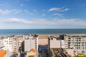 A coastal urban area with buildings, a parking lot, and a beach in the background. - High Waves Ostend (Ostend)