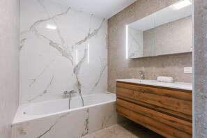 A bathroom with a marble wall, a wooden vanity, and a mirror. - High Waves Ostend (Ostend)
