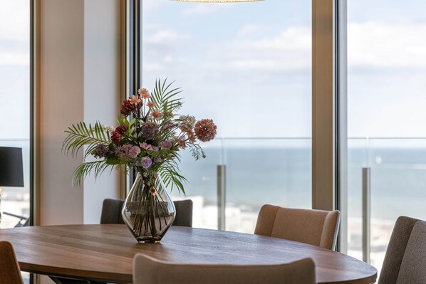 A table with a vase of flowers, a view of the ocean, and a modern interior. - High Waves Ostend (Ostend)