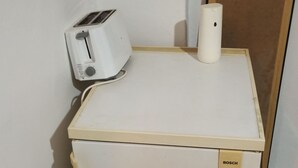 A compact refrigerator with a Bosch logo, a small toaster, and a roll of paper towels on top. - Renovated Studio Heart of City (Thessaloniki)