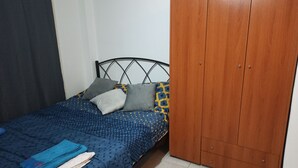 A single bed with a patterned bedspread, two pillows, and a folded towel. - Renovated Studio Heart of City (Thessaloniki)