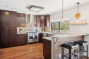 Una cocina moderna con armarios de madera oscura, una estufa de acero inoxidable y una isla grande con taburetes de bar.