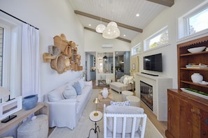 A spacious living room with a fireplace, a TV, and a dining area with a wooden cabinet.