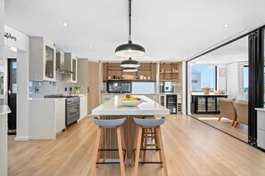 A modern kitchen with a central island, bar stools, and a pendant light.