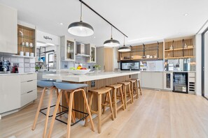 A modern kitchen with a central island, bar stools, and a built-in refrigerator. - Cest La Vie Beach Villa (St. Helena Bay)
