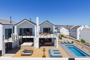 A modern two-story house with a balcony, a swimming pool, and a patio area. - Cest La Vie Beach Villa (St. Helena Bay)