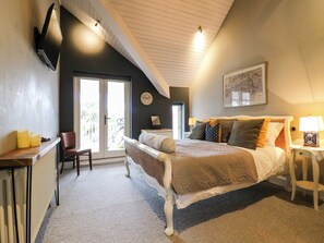 A bedroom with a bed, a chair, a desk, a radiator, a door, and a window. - River Haven - River Thames Frontage House (Thames Ditton)