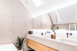 A modern bathroom with a large mirror, a white sink, and a wooden cabinet. - Bahnhofstrasse Designer Penthouse Private Rooftop (Zürich)