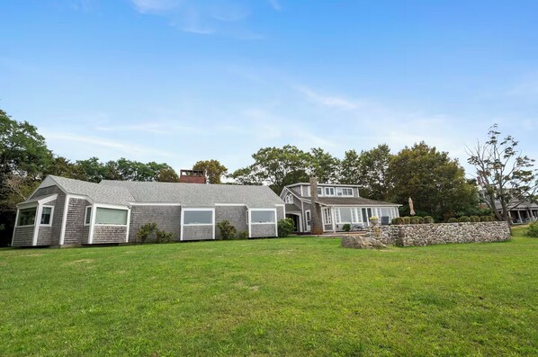 A two-story house with a large front lawn, a stone wall, and a garage. - Timeless Seaside Estate: 3 Lodgings, Private Beach (Gloucester)