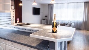 A modern kitchen with a central island, pendant lighting, and a flat-screen TV on the wall. - Hekmat Apartments Husum Nordsee (Husum)