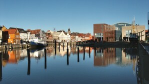 A calm waterfront with buildings and a boat docked. - Hekmat Apartments Husum Nordsee (Husum)