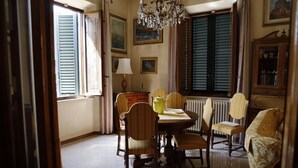 A dining area with a table, chairs, a chandelier, and a window with shutters. - Villa Lilly, a short walk from the historic center of Lucca (Lucca)