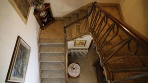 A staircase with a wooden handrail, a radiator, and a small round table with a lace tablecloth. - Villa Lilly, a short walk from the historic center of Lucca (Lucca)