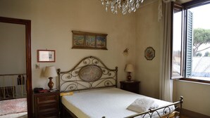 A bedroom with a bed, two bedside tables, a chandelier, a window with curtains, and a wall-mounted picture. - Villa Lilly, a short walk from the historic center of Lucca (Lucca)