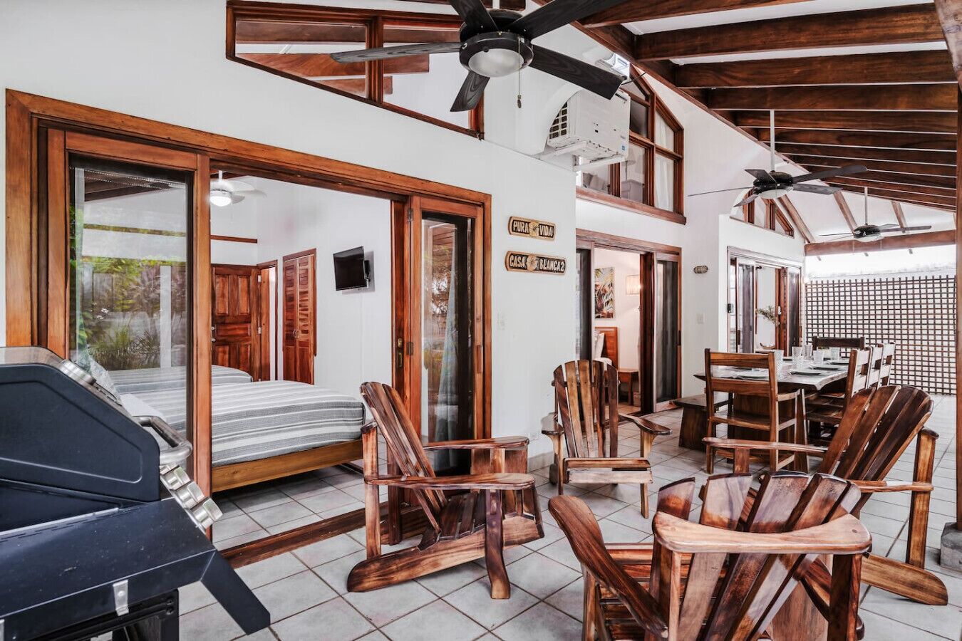 Une pièce spacieuse comprenant un lit, des chaises en bois, une table à manger et un ventilateur de plafond.