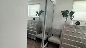 Ein Schlafzimmer mit Schiebetür, einem Schminktisch, einem Sessel und einer Pflanze.