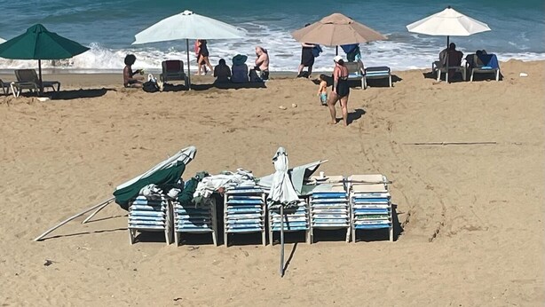 Une plage avec des parasols, des chaises longues et des gens qui se détendent au bord de l’eau.