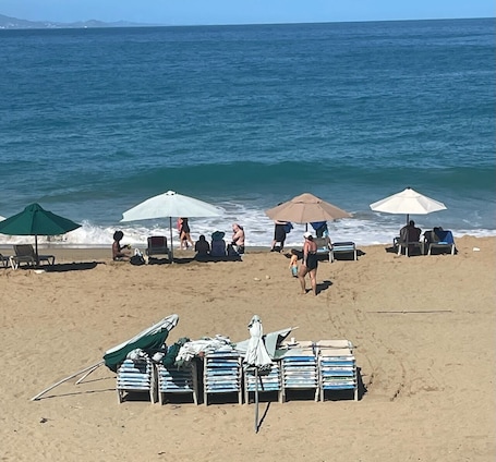 On the beach, white sand, sun-loungers, beach umbrellas. Hotel Restaurante La Cueva