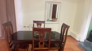 Un coin repas avec une table à plateau en verre et des chaises en bois.