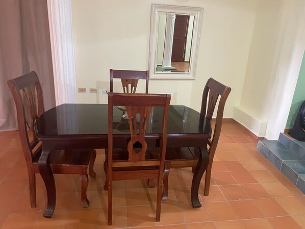 Een eethoek met een tafel met glazen blad en houten stoelen.