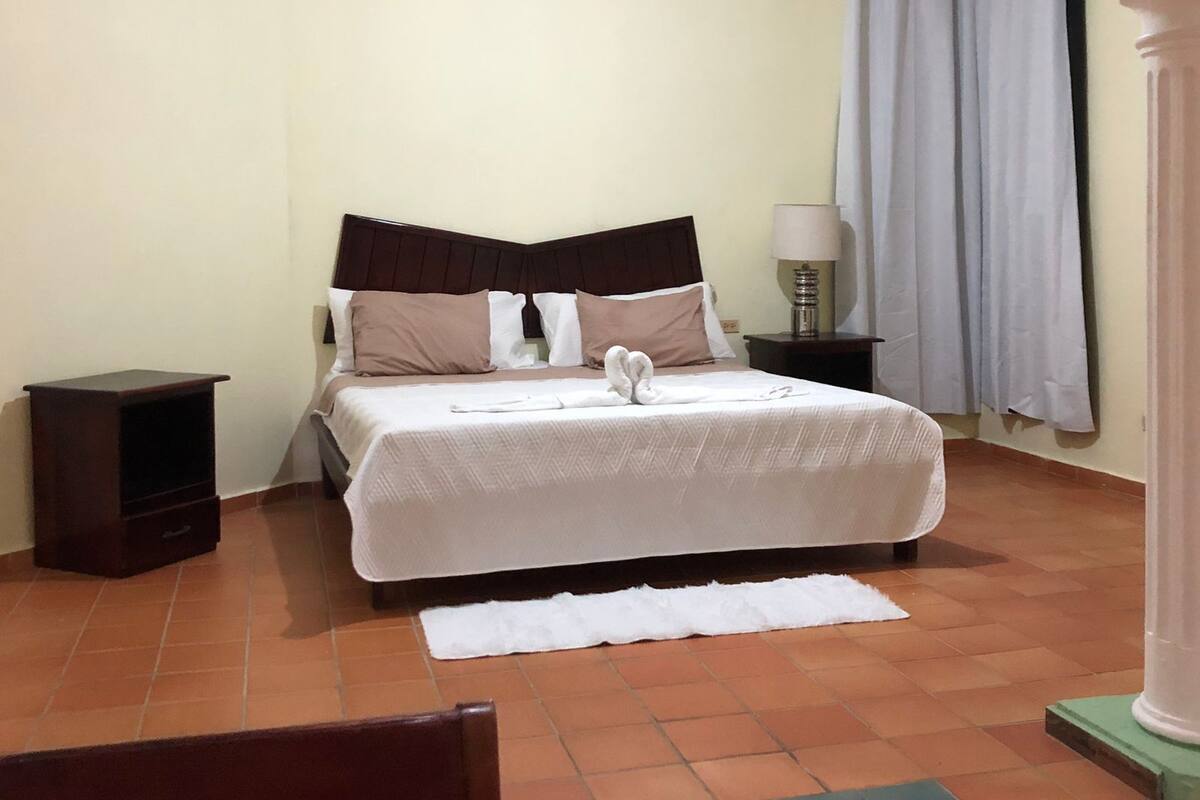 Une chambre bien rangée, avec un lit, une table de chevet et une chaise.