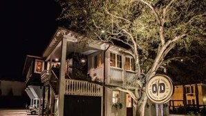 Una casa de dos pisos con un porche, un garaje y un árbol en la fachada.