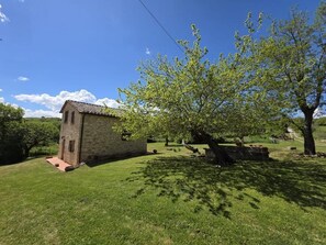 A small stone building with a tiled roof, surrounded by a well-maintained lawn and trees.