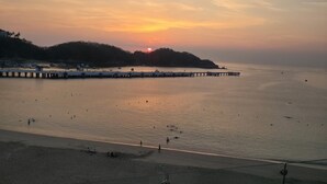 A coastal sunset view with a pier extending into calm waters, a sandy beach, and a hilly backdrop. - Stunning Beachfront Property (Crucecita)