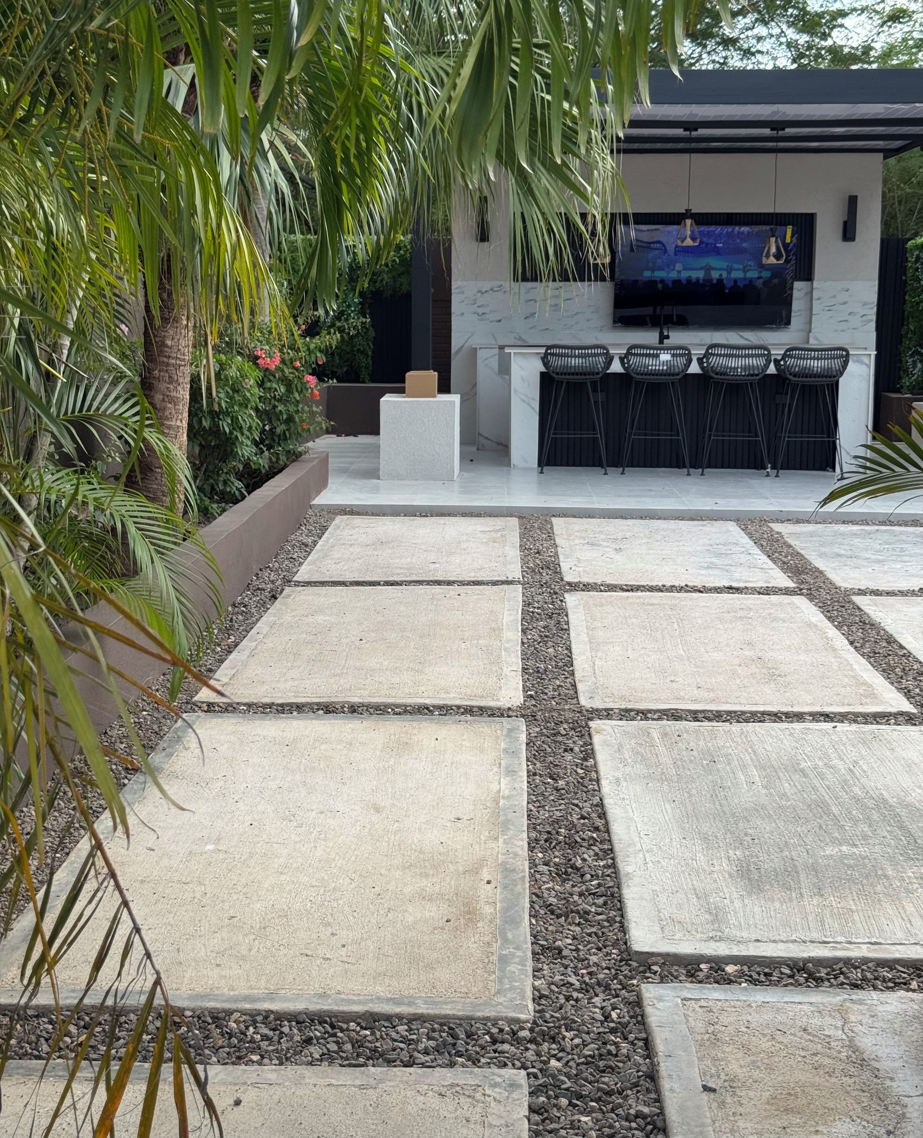 Eine Außenpatio-Terrasse mit Steinboden, einer Sitzgruppe und einem an der Wand befestigten Flachbildfernseher.
