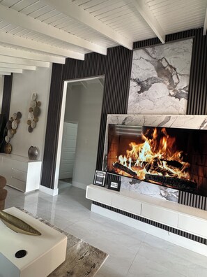 A modern living room with a fireplace, a sofa, and decorative wall art. - Luxury Oasis of New Harbour Village III (St. Catherine Parish)