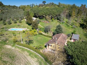An aerial view of a property with a swimming pool, a large tree, and a house with a sloped roof. - Holiday Home 'The Ancient Valley – Cautha' with Shared Pool, Shared Garden and Wi-Fi (Palaia)