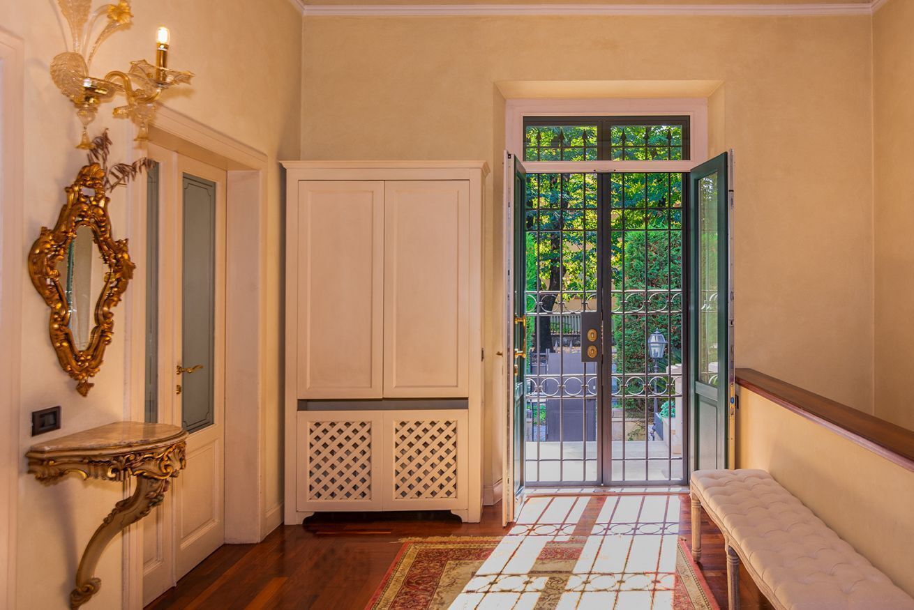 Un corridoio con una porta bianca, una panca e un tappeto decorato.