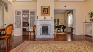 A spacious living room with a fireplace, a piano, and a dining area. - Villa Cecilia, facing Lucca's ancient city walls! (Lucca)