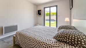 A bedroom with a bed, a radiator, a window, and a lamp.