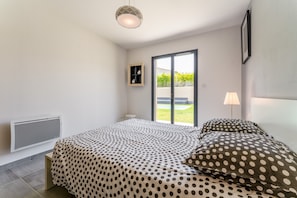 Un dormitorio con una cama, un radiador, una ventana y una lámpara.