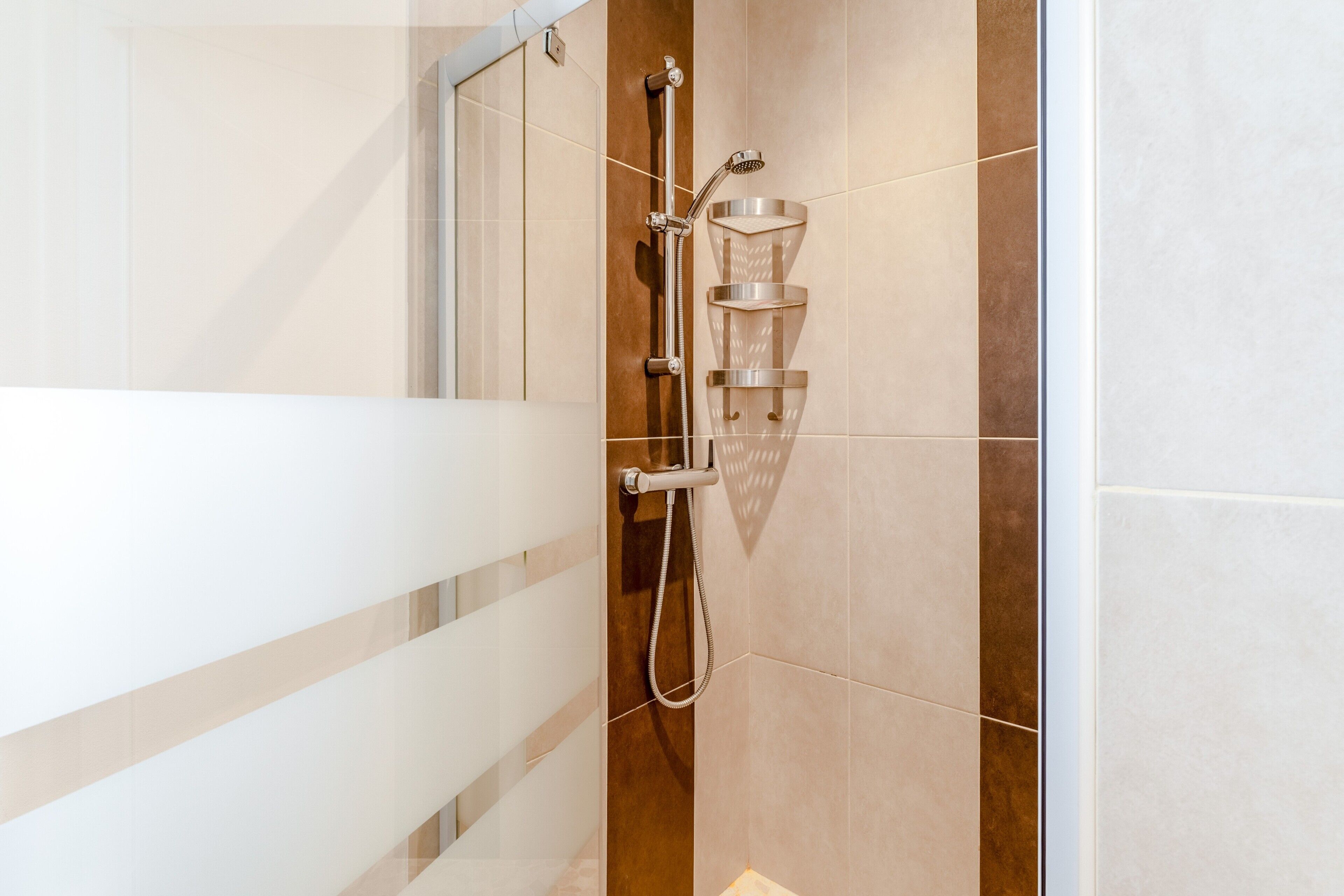 Eine Dusche mit Duschkopf und Wasserhahn an der Wand.