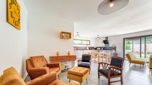 A modern living room with sofas, a coffee table, and a dining area with chairs.