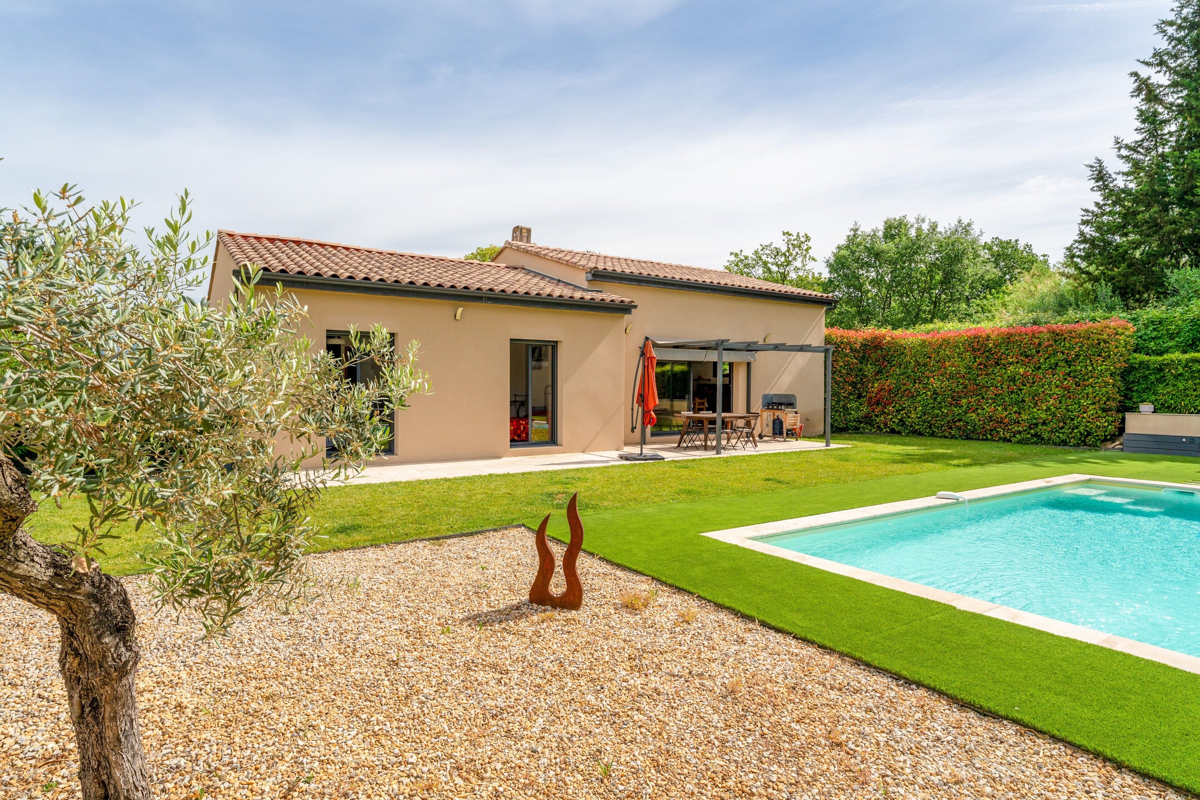 Una casa con piscina, patio y un jardín bien cuidado.