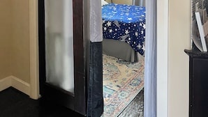 Una habitación con una cama, ventilador de techo y alfombra estampada.