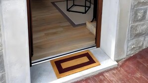 Una puerta que da a una habitación con piso de madera, una pequeña mesa y una silla.