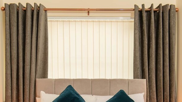 Un lit bien fait, recouvert d’une couvre-lit bleu foncé, avec deux oreillers et des serviettes pliées.