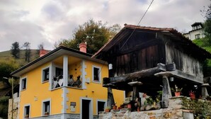 Un edificio amarillo con una escalera de piedra y una estructura de madera sobre pilotes.