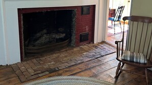 A room with a fireplace, a framed picture above it, a wooden chair, and a rug on the floor. - Historic Cape in quaint village of Jefferson Maine (Jefferson)