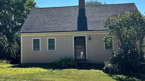 A single-story house with a chimney, a front door, and a small porch area. - Historic Cape in quaint village of Jefferson Maine (Jefferson)