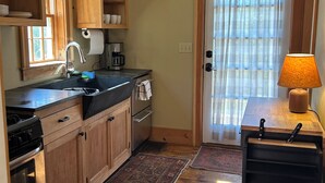 A compact kitchen with wooden cabinets, a built-in oven, a coffee maker, and a small refrigerator. - Historic Cape in quaint village of Jefferson Maine (Jefferson)