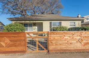 A single-story house with a front door, a garage door, and a wooden fence with a gate. - Prime Downtown Paso Guest House - Private & Wakable (Paso Robles)