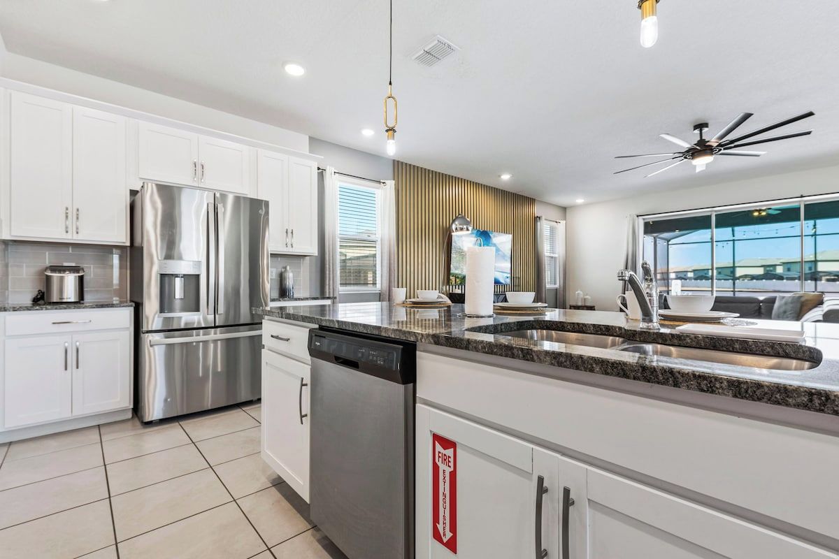 A modern kitchen with stainless steel appliances, a dishwasher, and a fire safety sign.