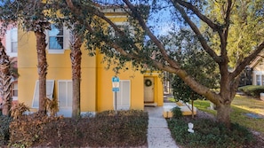 A yellow building with a covered entrance, a wheelchair accessibility sign, and a wreath on the door. - Themed rooms • Pvt pool • BBQ • Near Disney (Kissimmee)
