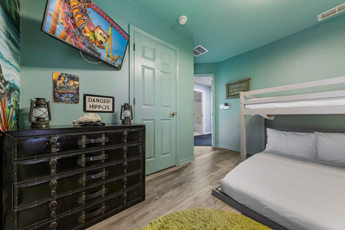 A bedroom with a bunk bed, a dresser, a door, and wall decorations.