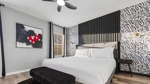 Ein modernes Schlafzimmer mit einem großen Bett, einem Deckenventilator und Wandtapete mit Muster.